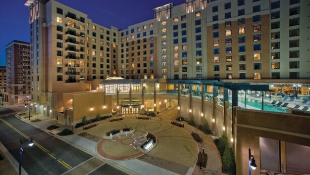 A multi-story hotel with a central courtyard, outdoor pool, and multiple balconies. - Club Wyndham National Harbor (Oxon Hill)