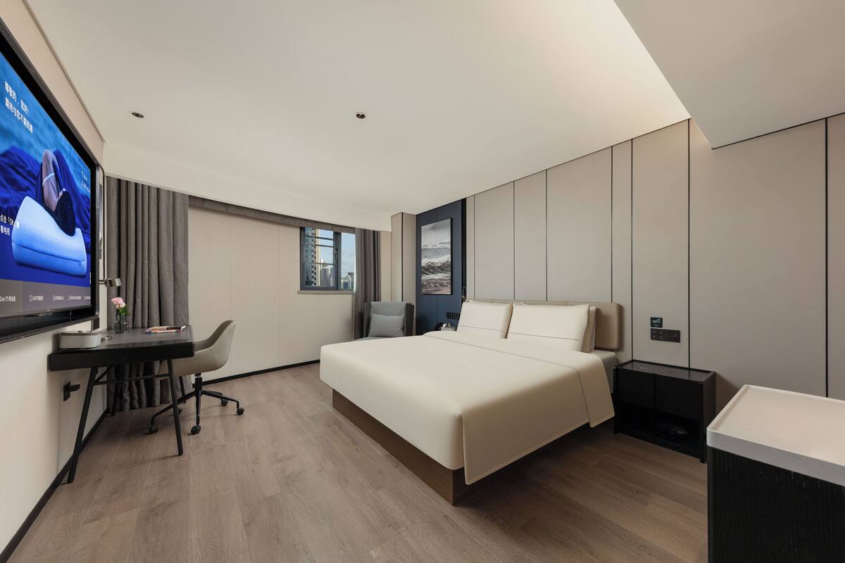 Une chambre d’hôtel moderne équipée d’un lit, d’un bureau et d’une télévision.