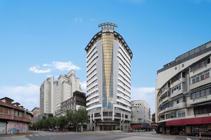 A tall hotel with a distinctive curved facade, multiple floors, and a prominent entrance. - Atour Hotel People's SquareMetroShanghai (Shanghai)