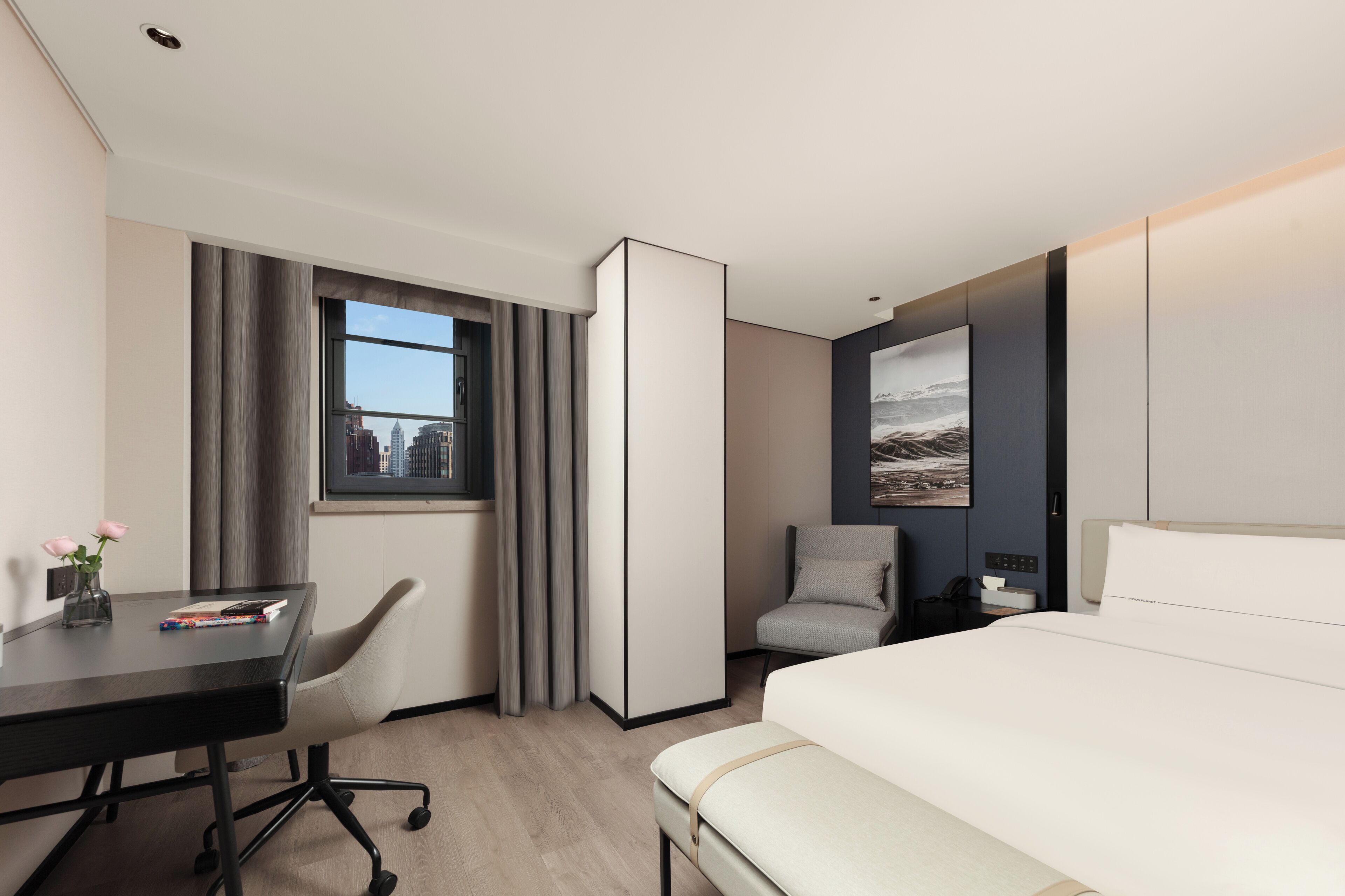Une chambre d’hôtel équipée d’un lit, d’un bureau, d’une chaise, d’une table de chevet et d’une fenêtre donnant sur la ville.