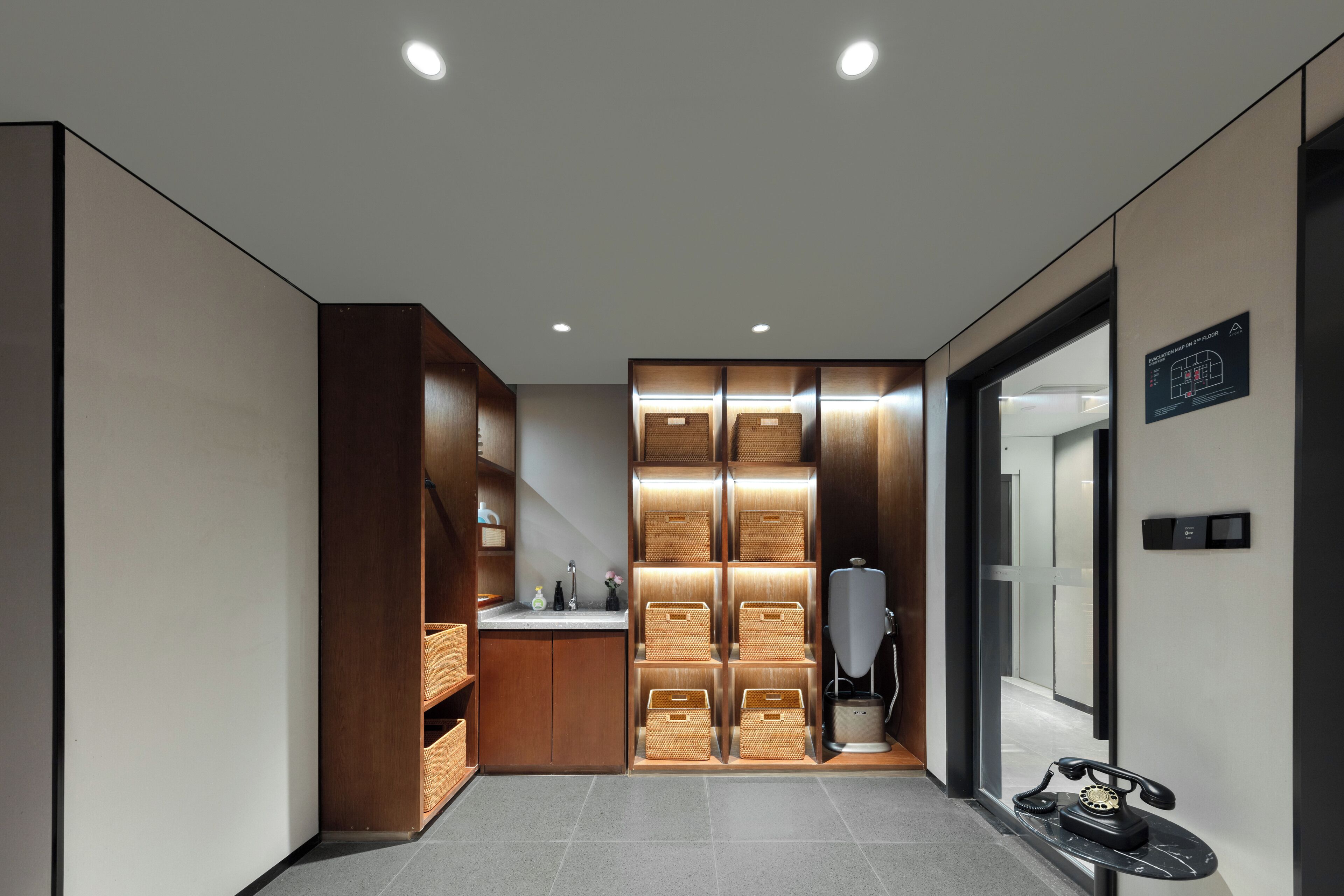 A modern hotel corridor with wooden storage units, a water dispenser, and a vintage telephone.