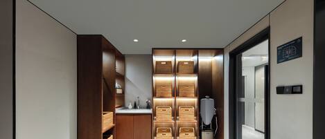 A modern hotel corridor with wooden storage units, a water dispenser, and a vintage telephone.