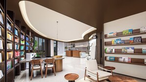 Eine moderne Bibliothek mit Bücherregalen, einer Leseecke und einem Empfangstresen.