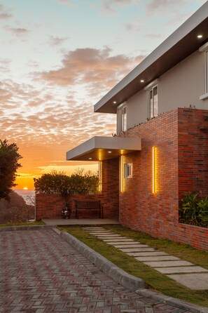 A modern house with a brick exterior, a flat roof, and a paved driveway leading to a front door. - 6k Sq Ft of Luxury Mountain View’s over the Pacific Ocean in SJDS! (San Juan Del Sur)