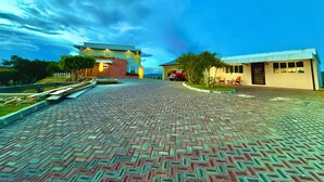A paved pathway leading to a building with a flat roof and a red vehicle parked nearby.