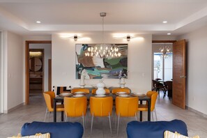 A dining area with a modern chandelier, a large abstract painting, and a table set for six. - 6k Sq Ft of Luxury Mountain View’s over the Pacific Ocean in SJDS! (San Juan Del Sur)