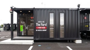 En modern, kompakt hotellbyggnad med namnet ”HOTEL R9 The Yard” och en skylt med texten ”RECEPTION”.