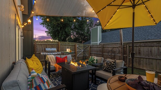 Une terrasse extérieure avec un foyer, des sièges et un barbecue.
