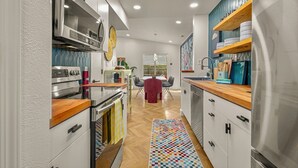 Une cuisine moderne dotée d’appareils électroménagers en acier inoxydable, de plans de travail en bois et d’un tapis aux couleurs vives.