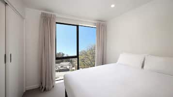Una habitación de hotel moderna con una cama grande, un armario y una ventana con cortinas.