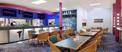 A restaurant with a blue and white color scheme, featuring a counter with a digital screen, wicker chairs, and a carpeted floor.