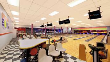 A bowling alley with multiple lanes, bowling balls, and seating areas.