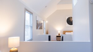 A modern bedroom with skylight, white walls, and a bed with a wooden headboard. - School 31 Lofts, Gallery:LOFT 646 (Rochester)