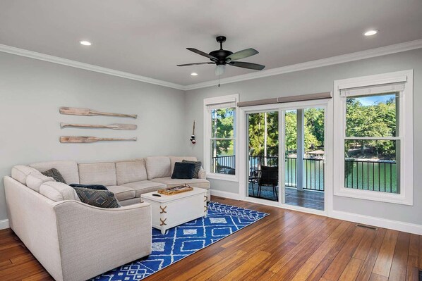 A living room with a sofa, coffee table, and a view of a deck and outdoor area.