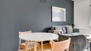 A modern living room with a round dining table, wooden chairs, a grey sofa with patterned cushions, and a framed artwork on the wall. - Blueground | Alsergrund, rooftop, nr Votivkirche (Vienna)