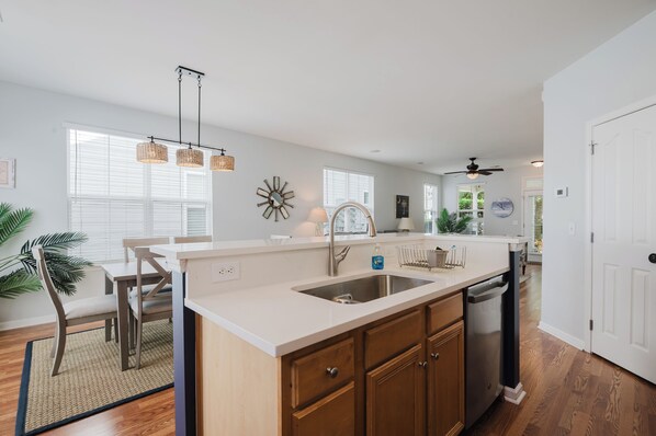 A modern kitchen with a white countertop, wooden cabinets, and a built-in dishwasher.