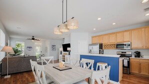 Une cuisine moderne avec des meubles en bois, un îlot central et un coin repas comprenant des chaises blanches et une table.