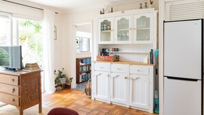 A kitchen with white cabinets, a refrigerator, a wooden counter, and a television. - Rustic, cosy one bedroom guesthouse. Just a short walk to Umina Beach! (Umina Beach)