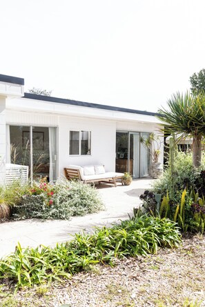 A modern house with a patio, a wooden bench, and a variety of plants. - Rustic, cosy one bedroom guesthouse. Just a short walk to Umina Beach! (Umina Beach)