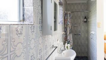 A bathroom with patterned tiles, a white sink, a mirror, and a shower area.