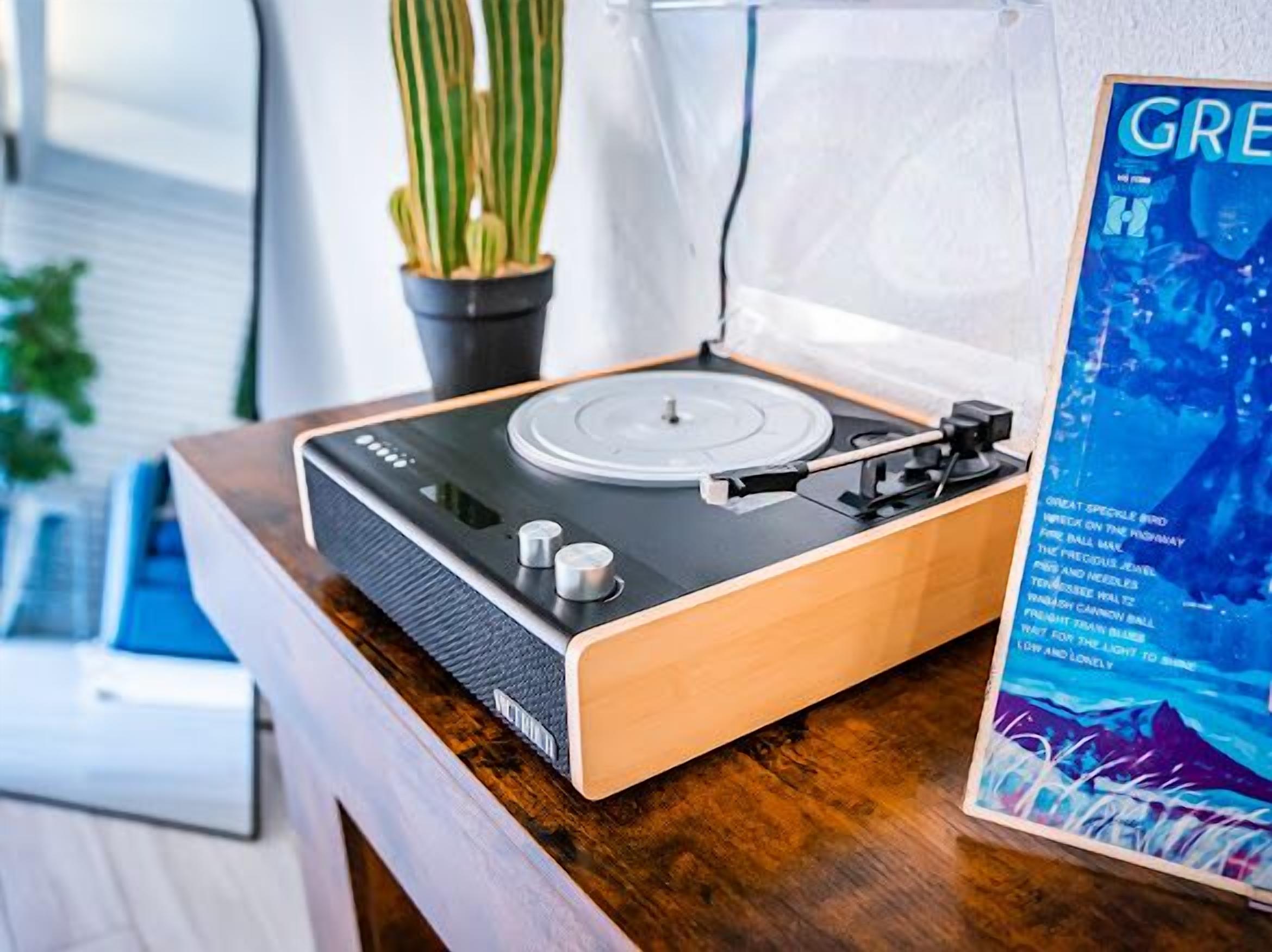 A turntable on a wooden table with a magazine beside it.