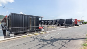 Eine Reihe von Containern an einem Dock, mit blauem Himmel und einem McDonald's Schild im Hintergrund.