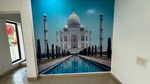 A room with a large mural of the Taj Mahal, a tiled floor, and a visible electrical outlet on the wall. - HOTEL AD RESEDENCY  (Agra)