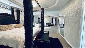 Un'ampia camera da letto con un letto a baldacchino, un grande specchio e vista sull'area soggiorno.