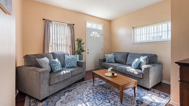 A living room with two grey sofas, patterned throw pillows, a wooden coffee table, and a blue patterned rug. - Only 8 min to Ohio State University! (Columbus)