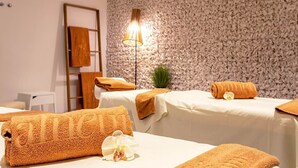 A spa room with two massage tables, each with a towel and an orchid. A floor lamp and a wooden ladder are visible. - Hotel White House (Halloluwa)