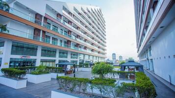 A multi-story hotel with outdoor seating areas and a view of the city skyline.