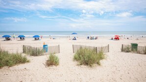 A beach with umbrellas, people, and a fence. - Oceanfront One-Bedroom Condo with Stunning Paradise Views (Myrtle Beach)