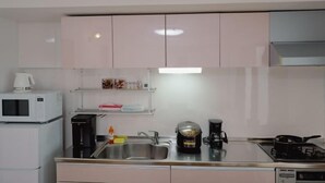 Une cuisine moderne avec des meubles blancs, un évier en acier inoxydable, une machine à café et une cuisinière.