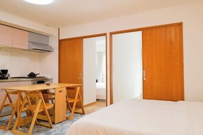 Une petite chambre comprenant un lit, un bureau et une kitchenette.