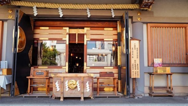 Un bâtiment traditionnel japonais, avec une entrée en bois, une enseigne et une petite table à l’extérieur.
