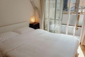 Une chambre à coucher avec un lit, une table de chevet et une fenêtre avec des rideaux.