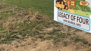 Señal de bienvenida para Legacy of Four en Van Buren, Misuri, con una ilustración de una caravana y una cabaña.
