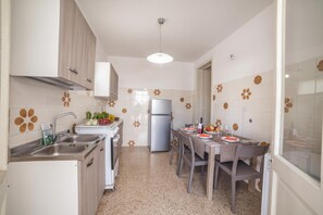 Een moderne keuken met een inbouwkoelkast, een spoelbak en een eethoek met een tafel voor vier personen.