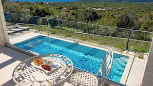 A balcony with a pool, a table with breakfast items, and a view of the sea and hills. - Villa Luka with Private Pool & Sea View, Labin, Croatia (Labin)