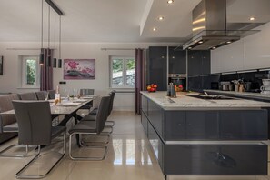 A modern kitchen with a central island, built-in appliances, and a dining area with a large table and chairs.