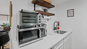 Una cocina con horno empotrado, microondas y cafetera.