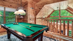 A wooden interior with a pool table, large windows, and a view of the outdoors. - Ever & After Cabin (Pigeon Forge)