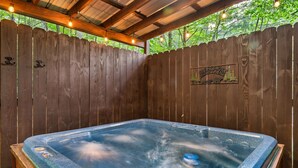 A hot tub under a wooden pergola with string lights, surrounded by a wooden fence. - Ever & After Cabin (Pigeon Forge)
