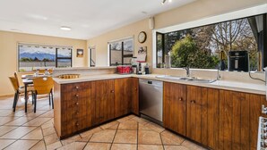 Une cuisine moderne avec des meubles en bois, un lave-vaisselle et une grande fenêtre donnant sur un paysage de arbres et de montagnes.