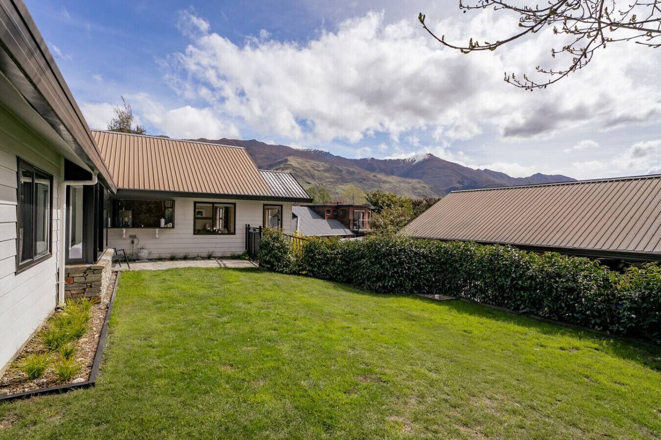 A house with a well-maintained lawn and a mountain backdrop.