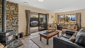 Un salon chaleureux avec un mur en pierre, une cheminée, un canapé et une vue sur l’extérieur.