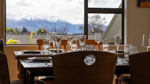 Une table à manger dressée avec des verres et des couverts, et une vue sur les montagnes par la fenêtre.