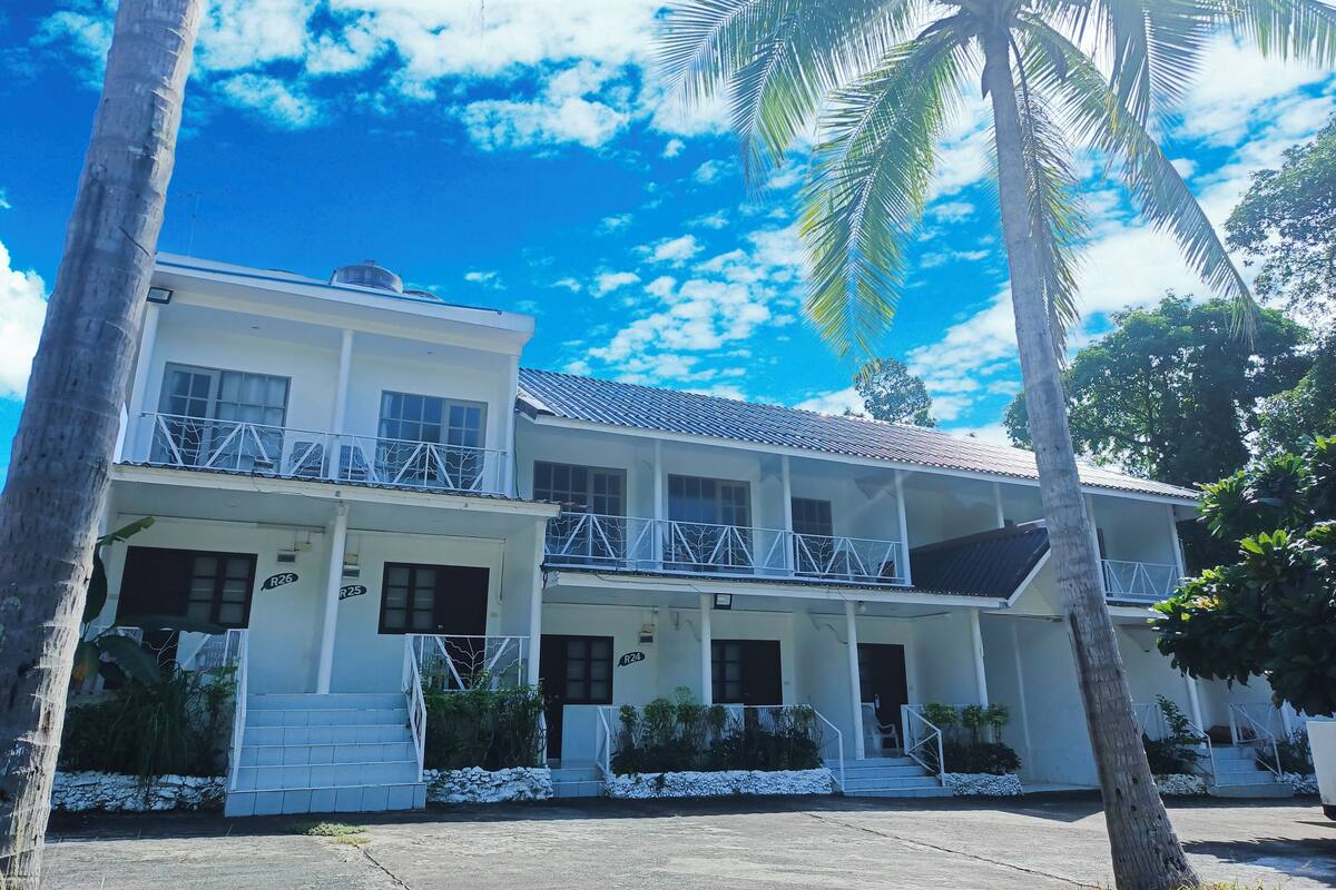 A two-story building with a balcony, white exterior walls, and a tiled roof.
