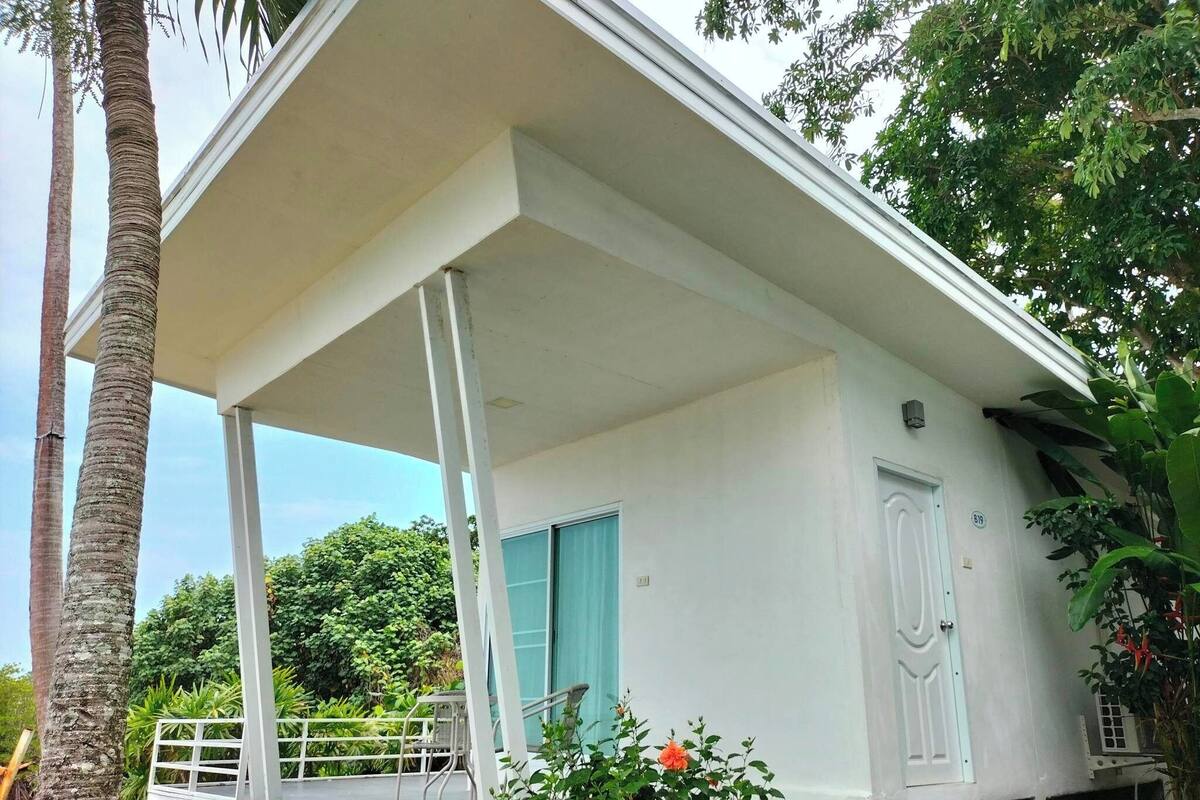 A white building with a covered porch, a door, and a window.