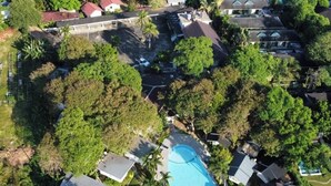An aerial view of a residential area with a swimming pool surrounded by houses and lush greenery. - White house bailan resort (Ko Chang)